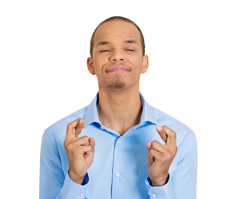Closeup portrait of young handsome hopeful man crossing fingers, student, worker wishing, praying for miracle, hoping for best, isolated on white background. Positive human emotions, facial expression Closeup portrait of young handsome hopeful man crossing fingers, student, worker wishing, praying for miracle, hoping for best, isolated on white background. Positive human emotions, facial expression